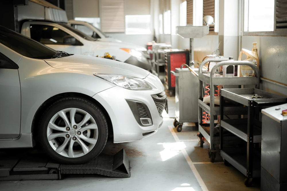 Atelier automobile, mécanicien portant des gants rouges effectue un polissage ou meulage sur un disque de frein