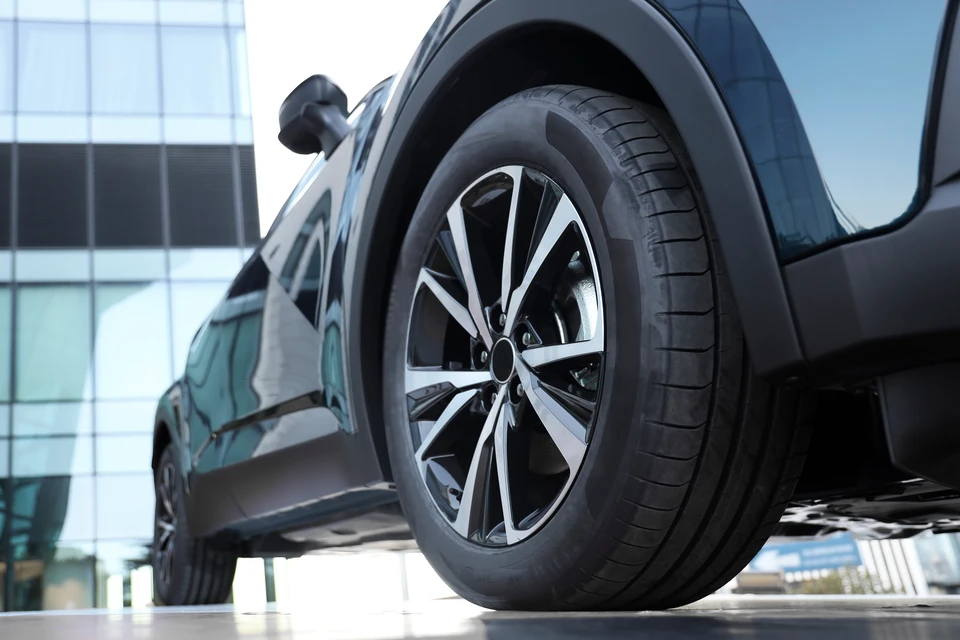 Fond blanc neutre présentant deux roues agricoles noires en caoutchouc avec crampons prononcés, positionnées l'une à plat et l'autre en position verticale pour montrer le profil latéral