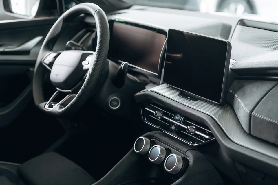 Mécanicien automobile en combinaison jaune travaillant sous le capot ouvert d'un véhicule dans un garage